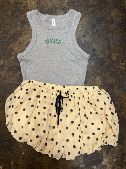 Gray racerback tank top with green HERD embroidery, styled with cream polka dot shorts