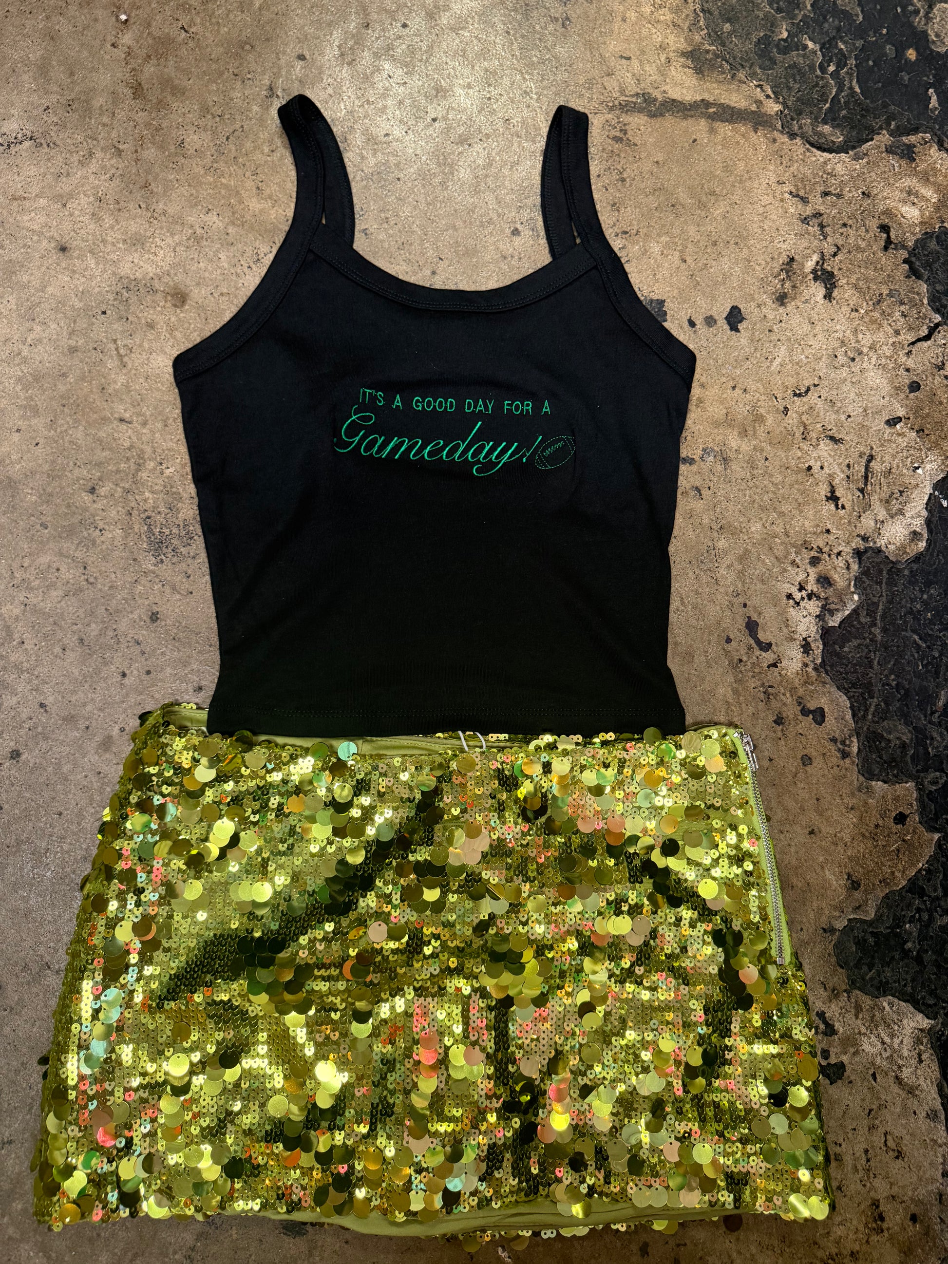 Black tank top with green Gameday graphic, paired with gold sequin mini skirt