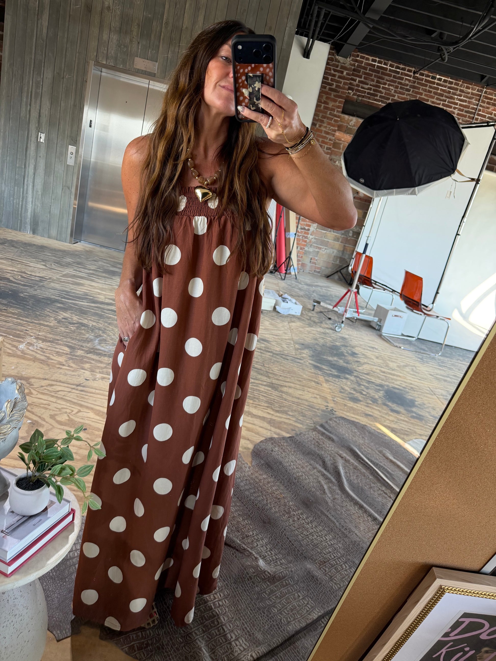 Brown and white polka dot sleeveless maxi dress with smocked neckline and gold necklace