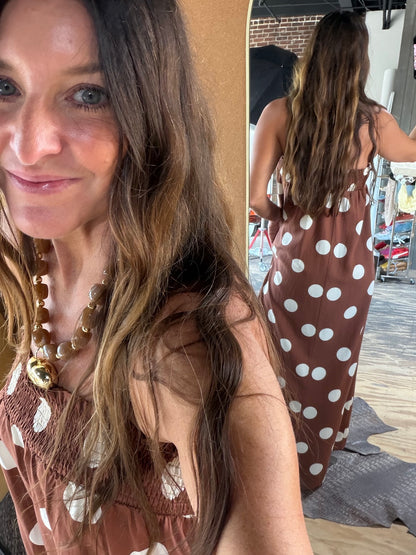 Brown polka dot smocked maxi dress with white dots, worn by brunette woman