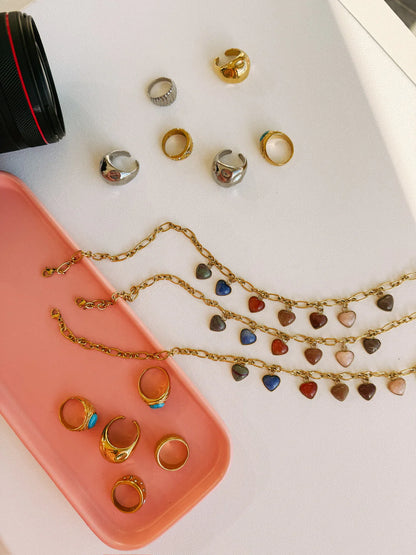 Gold chain necklaces with colorful stone heart charms in blue, red, and pink