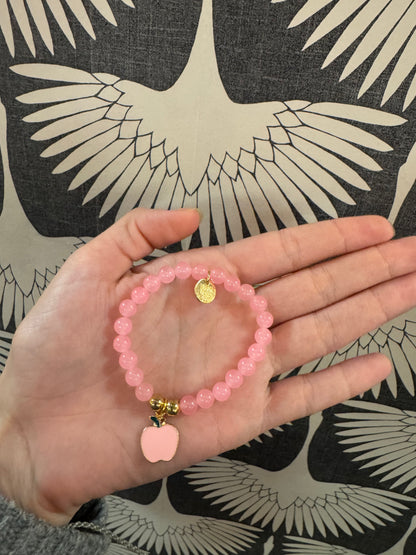 Pink beaded stretch bracelet with gold coin charm and pink enamel apple pendant