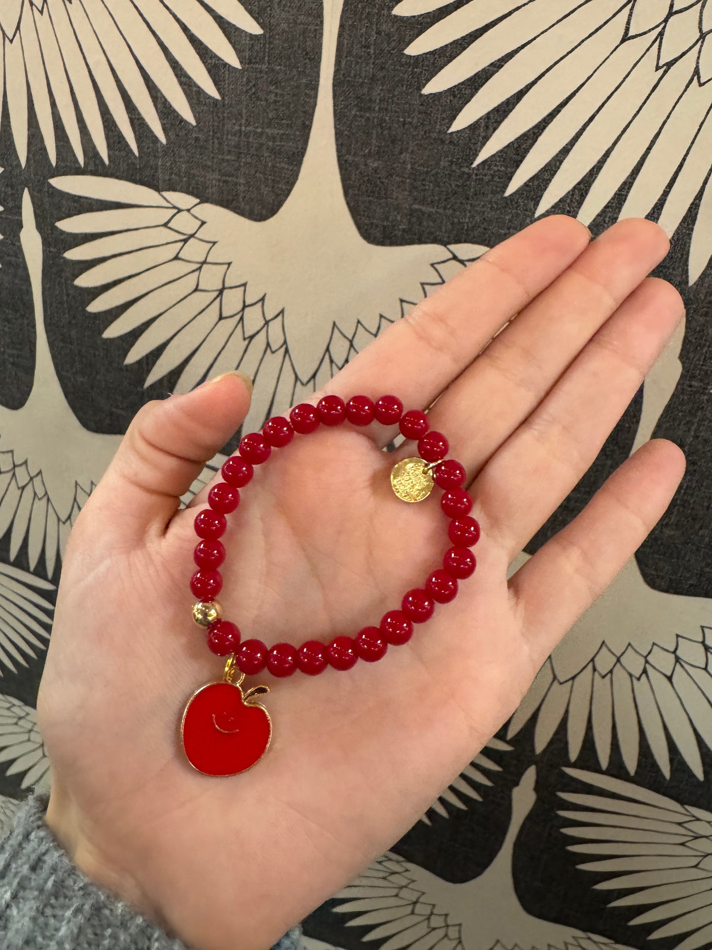 Red beaded stretch bracelet with red enamel apple charm and gold coin charm