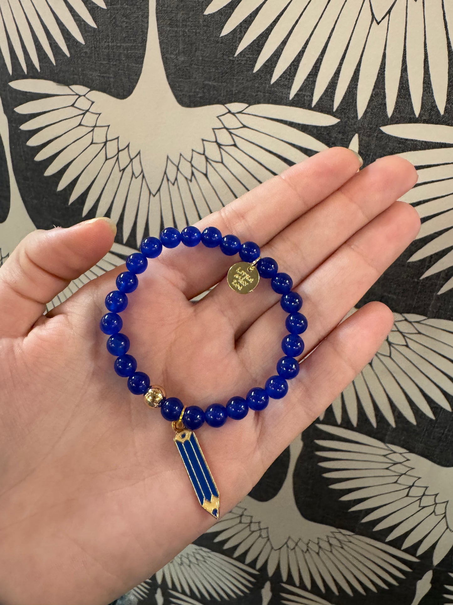 Blue beaded stretch bracelet with gold pencil charm and engraved coin pendant