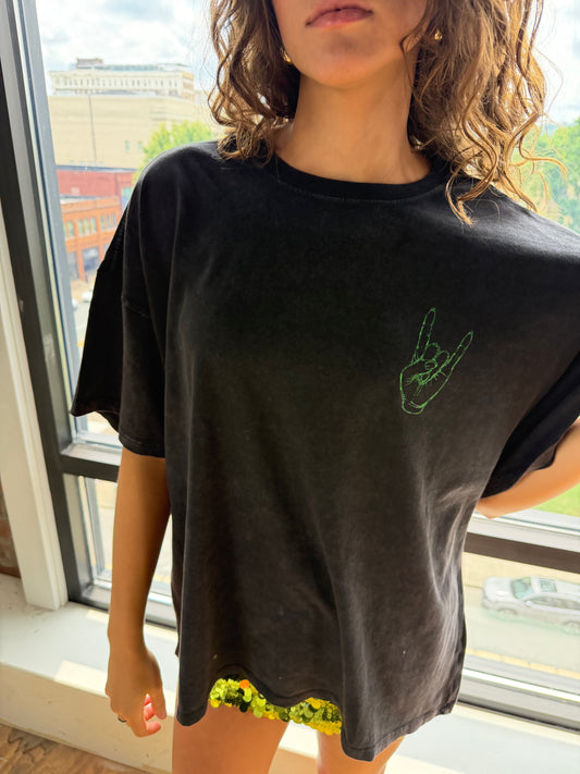 Oversized black tee with green metallic rock hand gesture graphic on chest