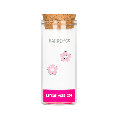 Pink flower stud earrings displayed inside a small glass bottle with cork stopper