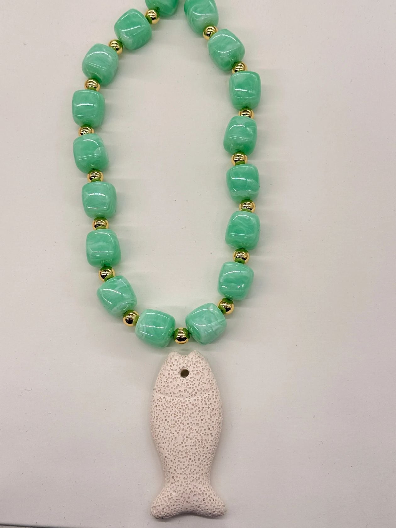 this necklace is a bold, coastal inspired statement piece with an earthy, textured feel. designed with chunky resin beads and gold accent beads. a lava stone fish pendent adds a unique ocean-inspired detail, giving the piece a playful yet elevated beachy edge. 