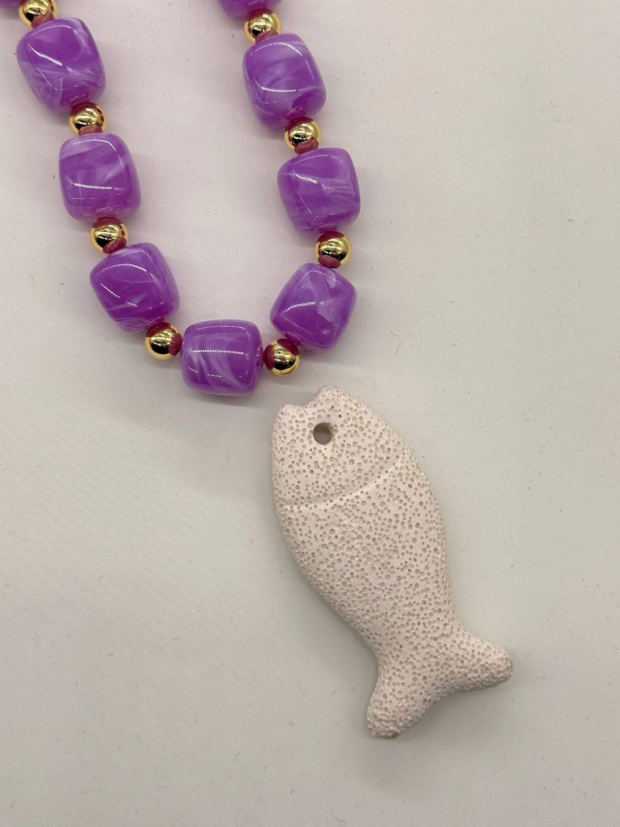 Purple beaded necklace with gold spacers and white lava stone fish pendant