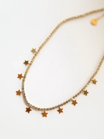 Gold crystal tennis necklace with dangling gold star charms along the front