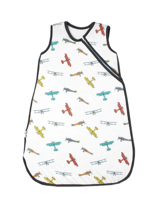 White baby sleep bag with colorful vintage biplane print and black trim