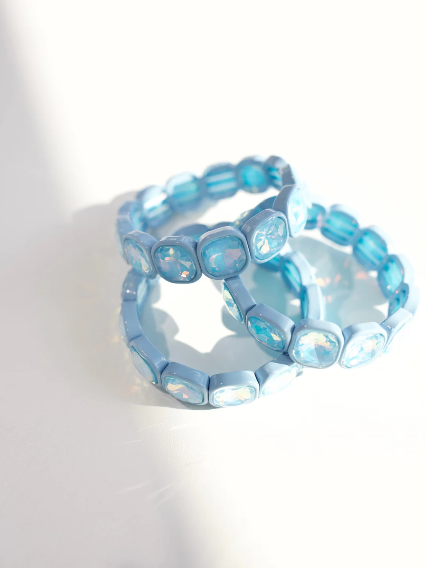 Stacked light blue stretch bracelets with cushion-cut iridescent crystal stones