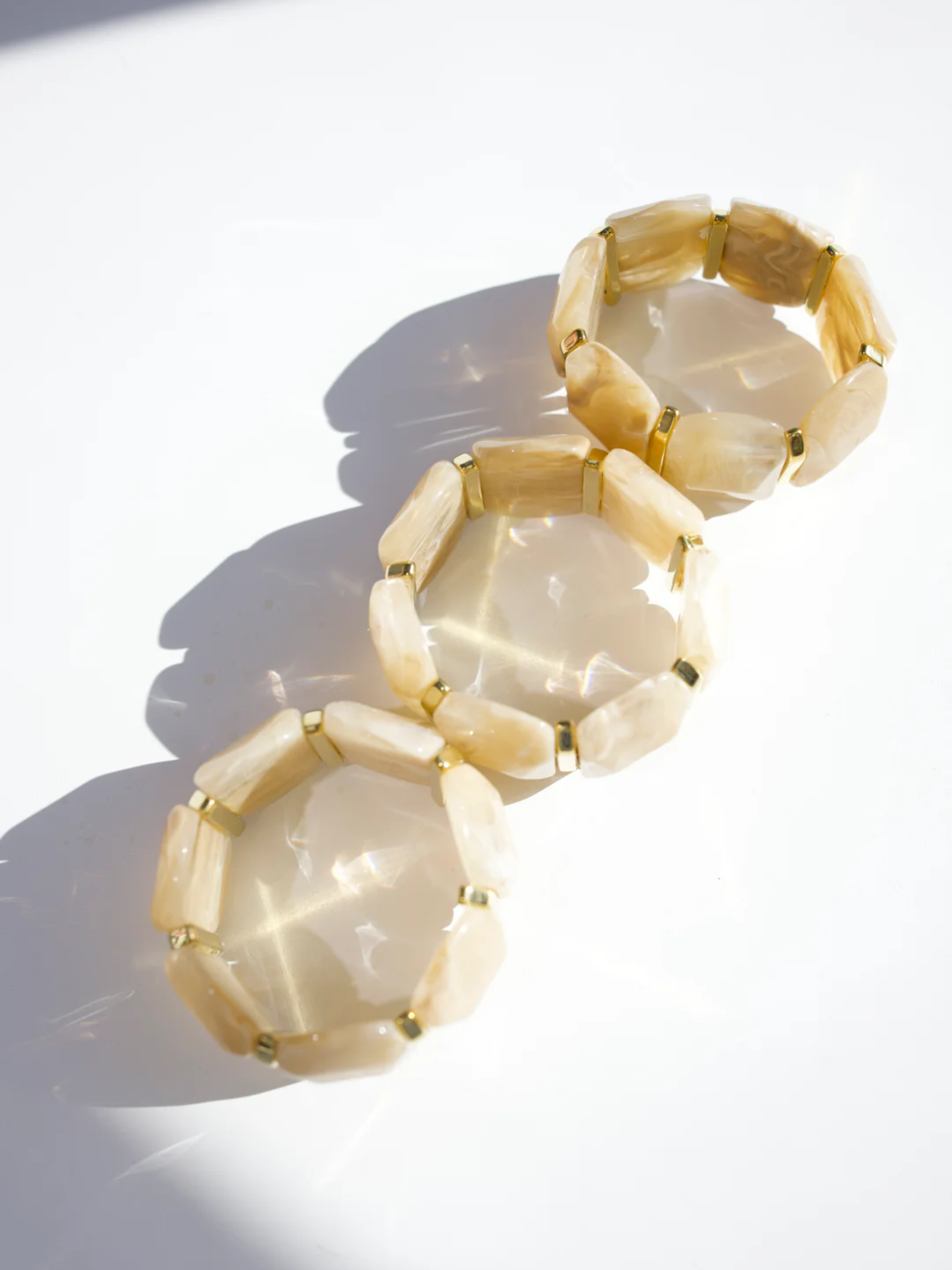 Three cream stone stretch bracelets with gold spacer beads stacked together