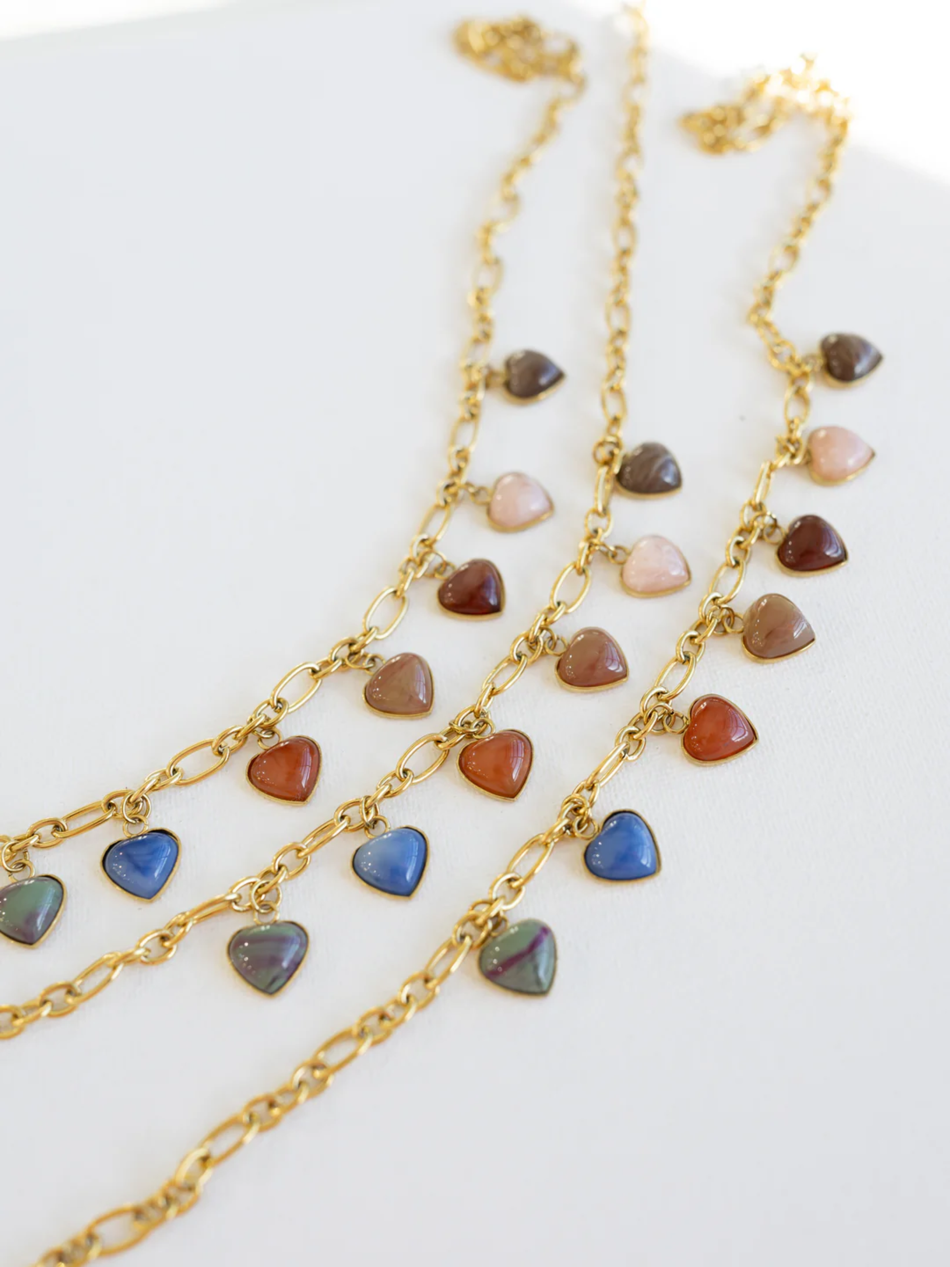 Gold chain necklace with multicolor heart-shaped stone charms in earthy and blue tones