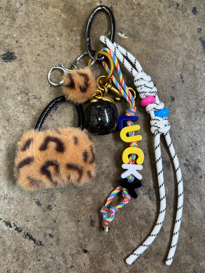 Bag charm with a fuzzy leopard purse, black glittery apple, and rope with "lucky" text