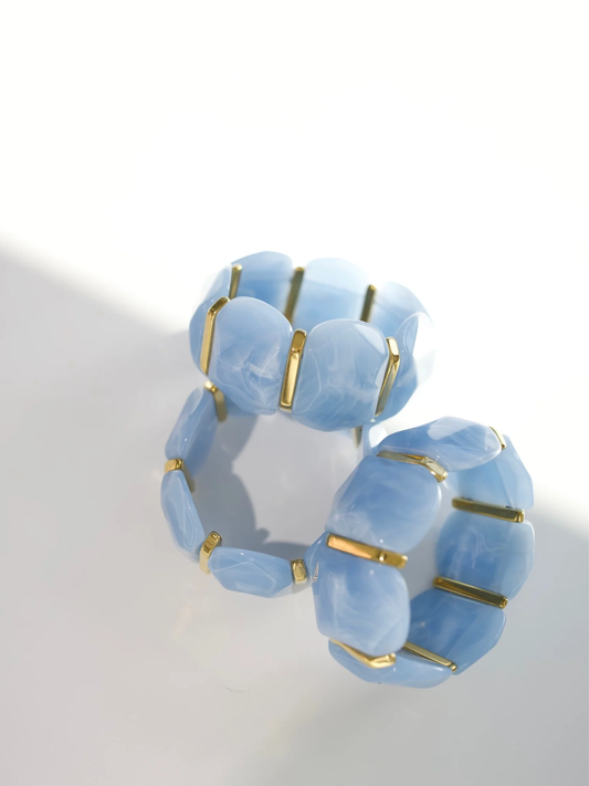 Light blue marbled stretch bracelet with gold-tone bar spacers between rounded tiles