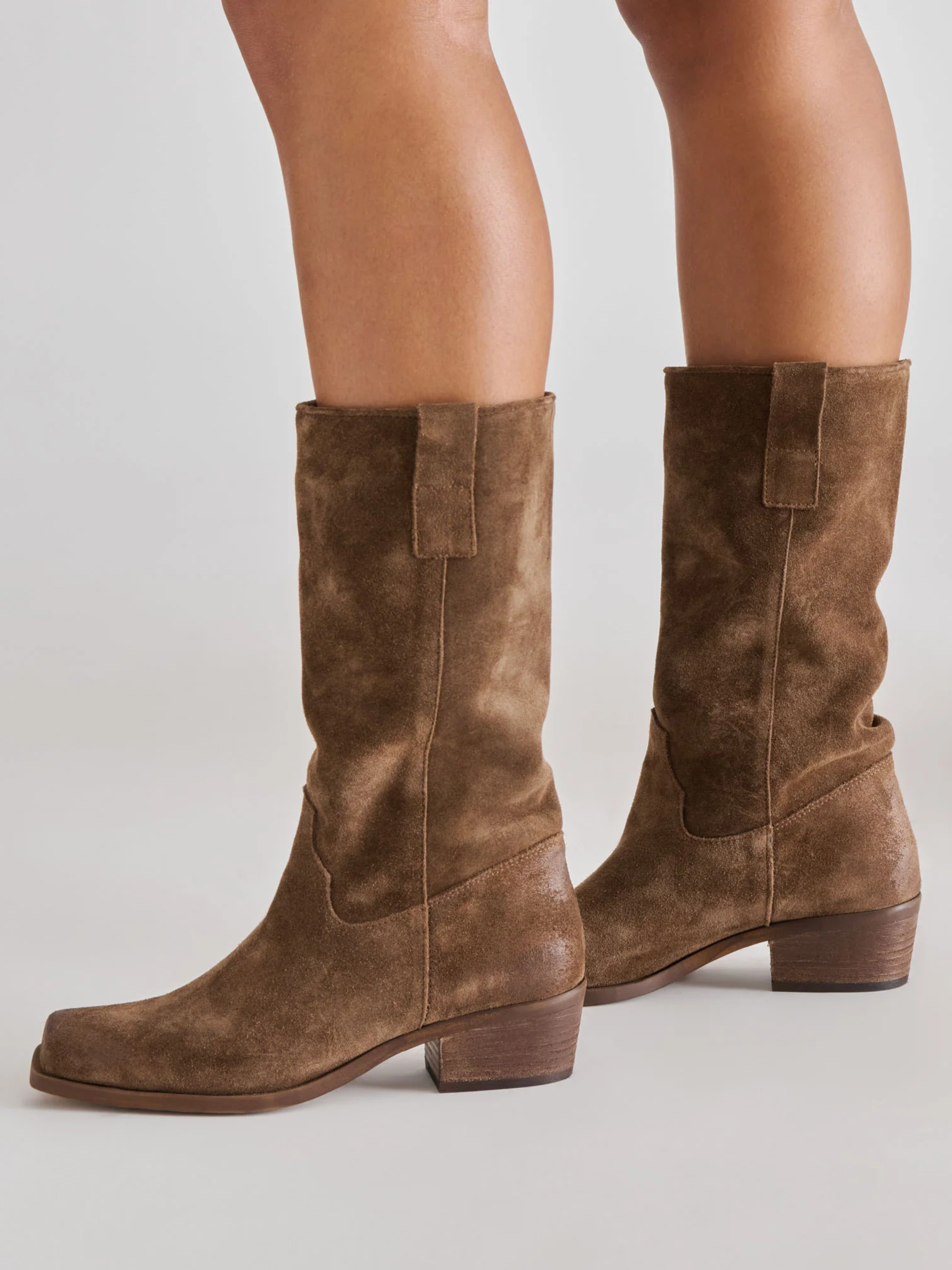Mid-calf chocolate brown suede boots with block heel and pull tab on model