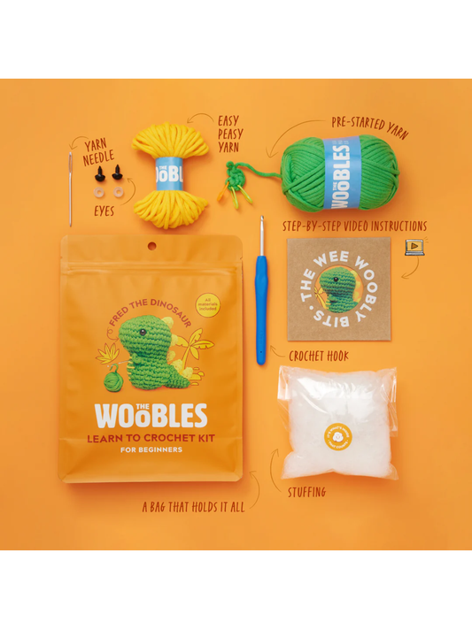 Green dinosaur crochet kit with yarn, hook, stuffing, eyes, and needle on orange background