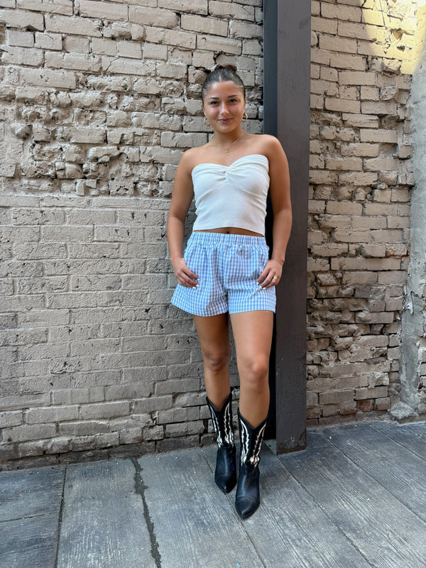 blue gingham print boxer shorts, white ribbed tube top and black cowgirl boots