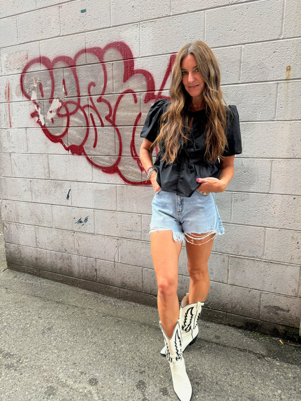 black blouse, denim cut off, and white cowgirl boots