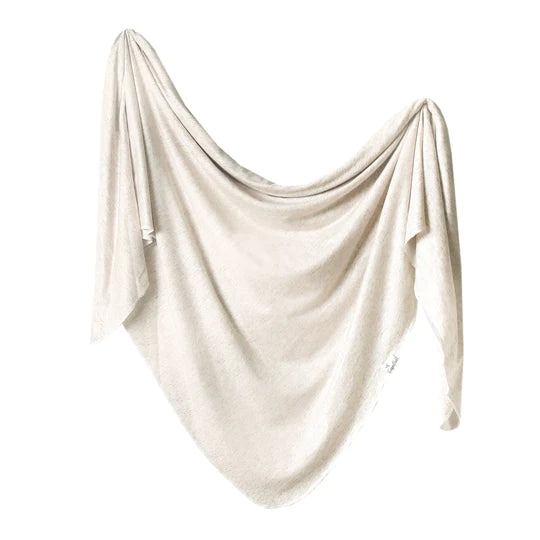 Copper Pearl swaddle blanket in oat, a soft cream knit fabric draped elegantly